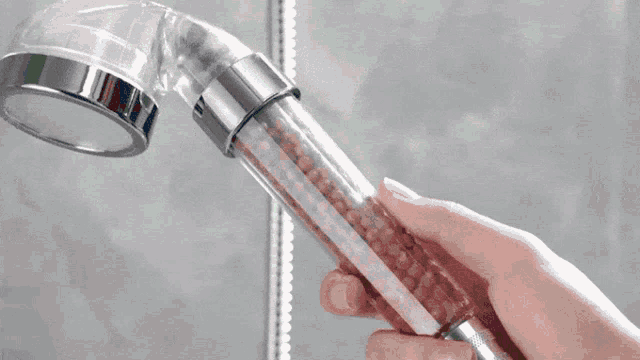 a person is holding a shower head with green lights on it