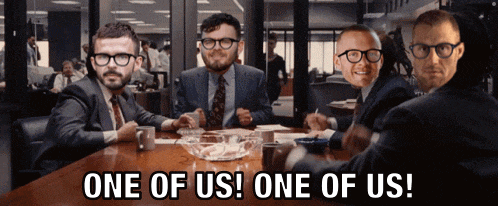 a group of men are sitting around a table with one of them saying one of us one of us