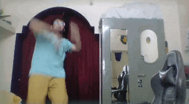 a man in a blue shirt and yellow shorts is dancing
