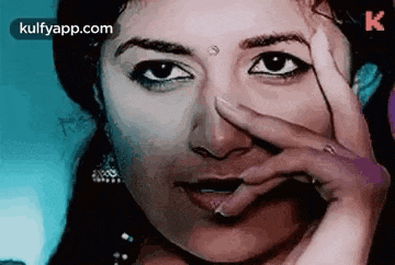 a woman is covering her face with her hand and looking at the camera .
