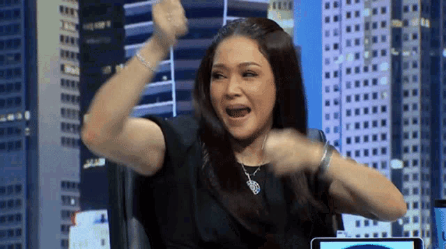 a woman is sitting in front of a computer with her arms in the air and her mouth open