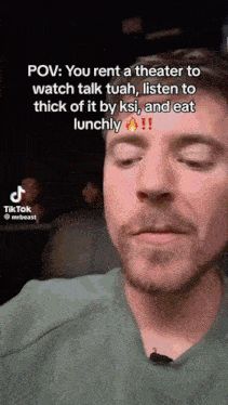 a man with a beard is sitting in a theater watching a movie and talking to someone .