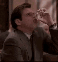a man in a suit is drinking a glass of beer .