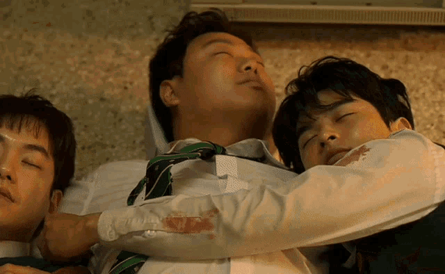 a man in a white shirt and tie is laying on another man 's chest