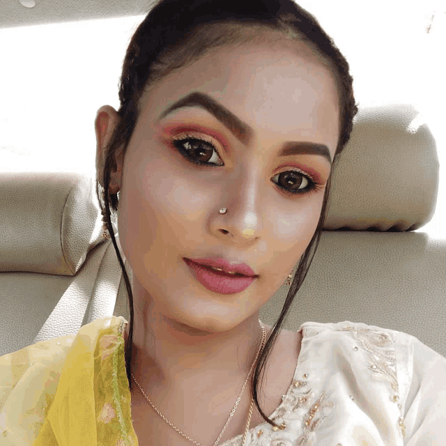 a woman with a nose ring is wearing a white top
