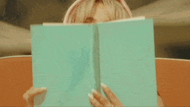 a woman covering her face with a book