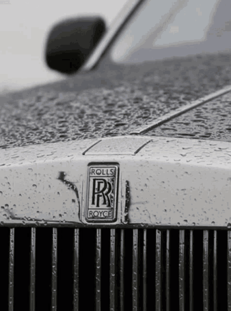 a close up of a rolls royce car with rain drops on it