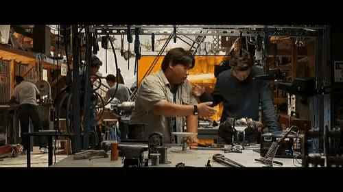 two men are working on a machine in a workshop with a sign that says danger on it