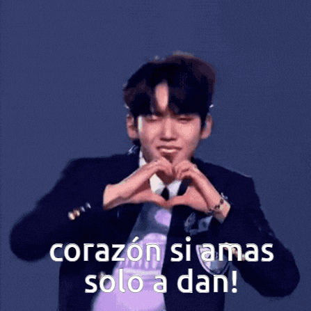 a man in a suit and tie is making a heart shape with his hands