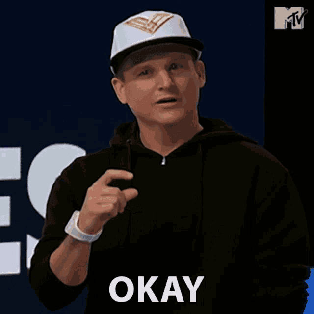 a man wearing a baseball cap and a black hoodie says okay