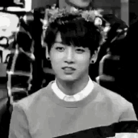a black and white photo of a young man wearing a striped sweater .