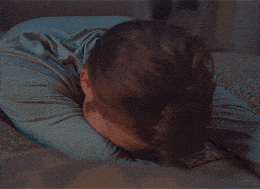 a man in a grey striped shirt is laying on his stomach