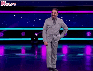 a man in a suit and tie is standing on a stage in front of a purple background .