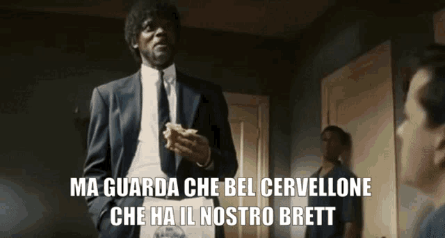 a man in a suit and tie holds a piece of bread and says ma guarda