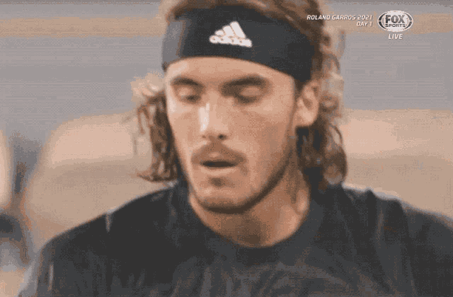 a close up of a man wearing a headband with the word adidas on it
