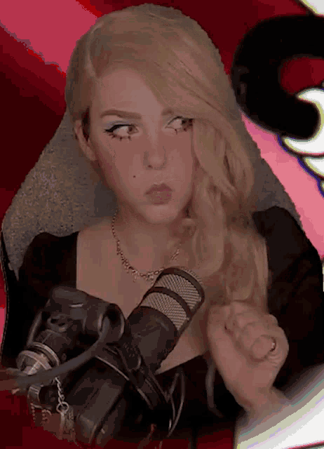 a woman with blonde hair is sitting in front of a microphone and a camera