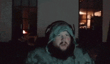 a man with a beard wearing headphones and a hoodie is making a funny face