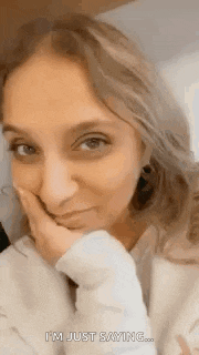 a close up of a woman 's face with her hand on her chin and the words `` i 'm just saying '' .