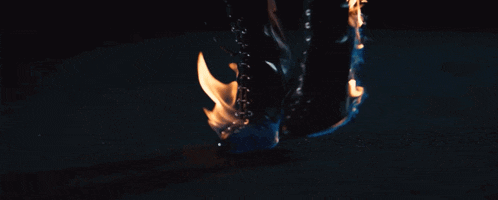 a person 's feet are on fire with a black shoe in the foreground