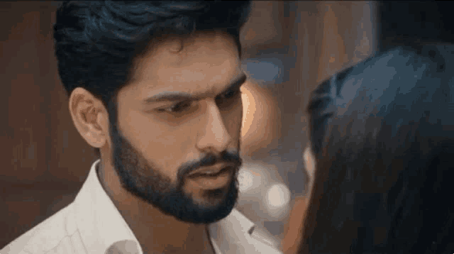 a man with a beard is looking at a woman 's face .
