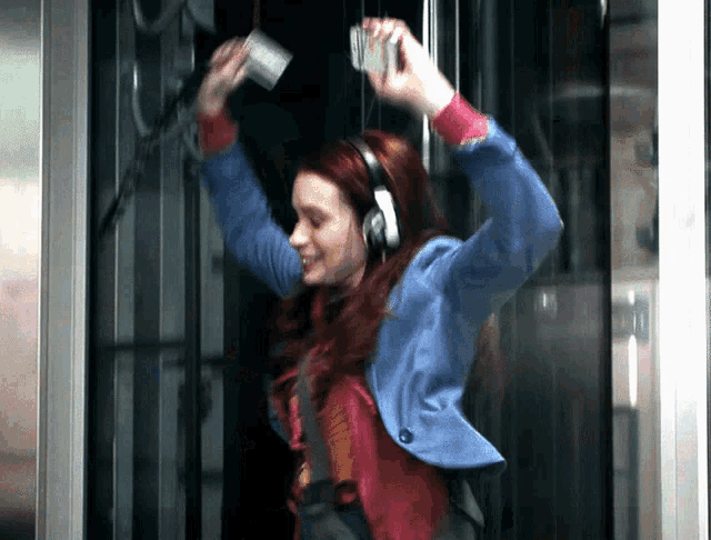 a woman wearing headphones is dancing and holding a cup