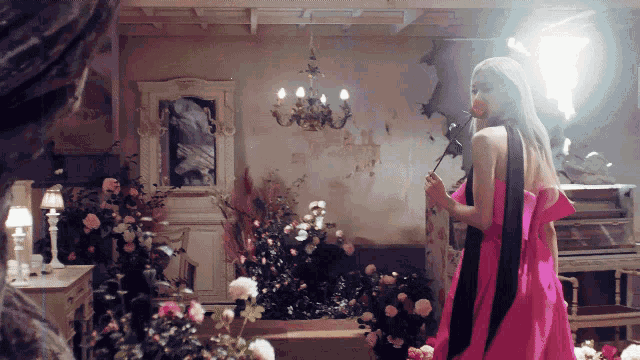 a woman in a pink dress holds a rose
