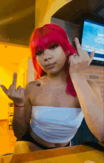 a woman with red hair and a white top is giving the middle finger