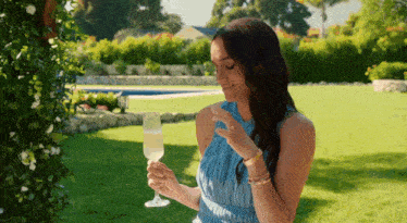 a woman in a blue dress is holding a glass of wine in her hands .