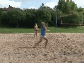 two women are playing volleyball on a sandy court