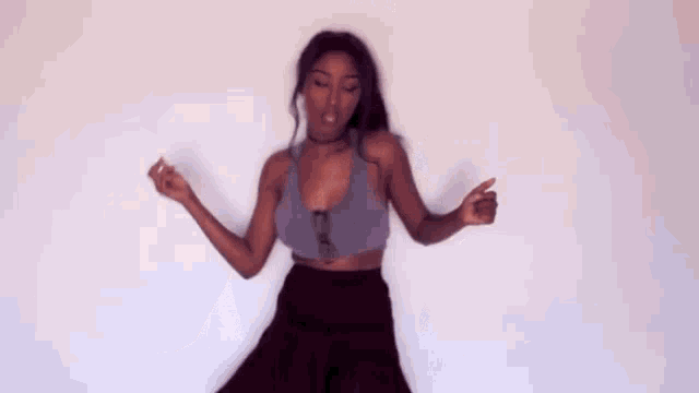 the woman is wearing a purple tank top and black pants and is dancing .