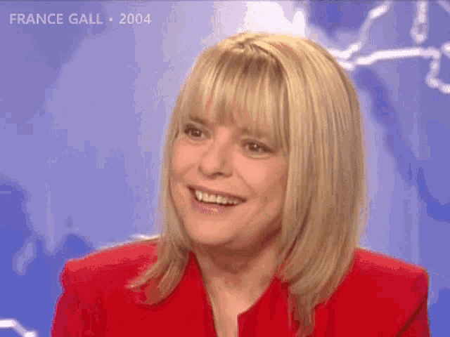 a woman in a red jacket is smiling in front of a blue background with the year 2004 on it