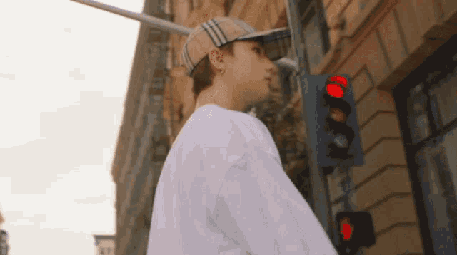 a man wearing a hat stands in front of a red light