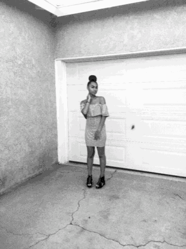 a woman in a dress stands in front of a white garage door