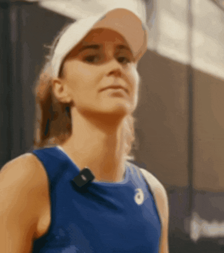 a woman wearing a blue tank top and a white hat with the letter a on it