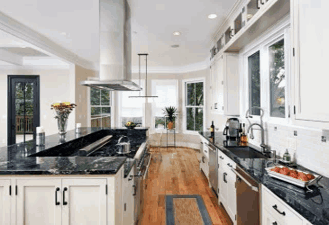 a kitchen with black counter tops and white cabinets and stainless steel appliances