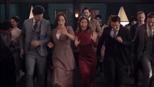 a group of people in suits are dancing together in a room