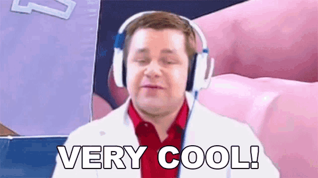 a man wearing headphones and a lab coat is saying `` very cool ! ''