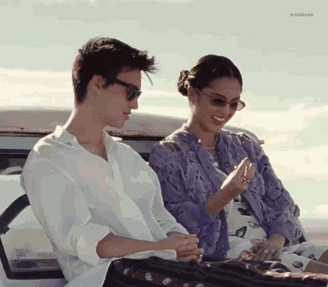 a man and a woman are sitting in the back of a car looking at their phones