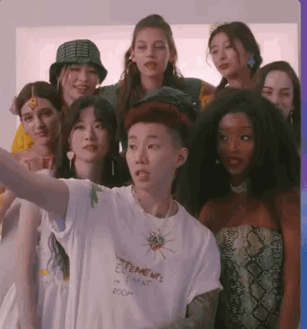 a group of people are posing for a picture and one of them is wearing a white shirt that says elements in instant room