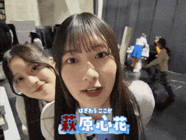 two girls are posing for a picture and one has chinese writing on her shirt