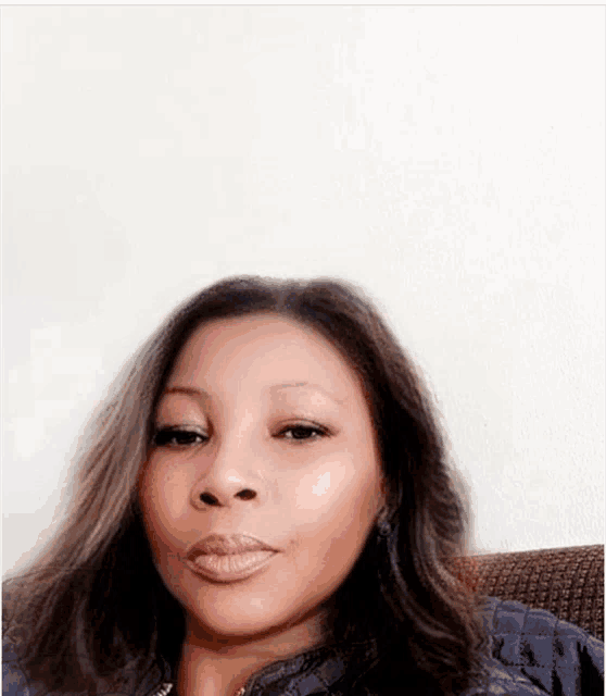 a woman with long dark hair is sitting on a couch .
