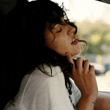a woman sitting in a car with her eyes closed and her mouth open
