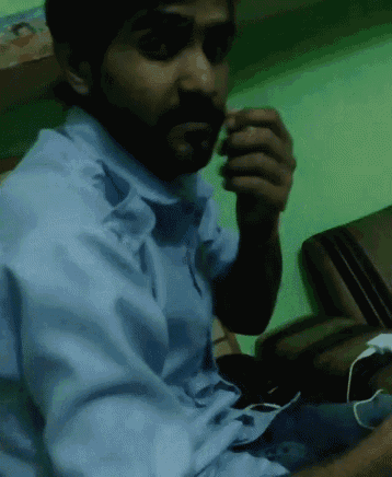 a man in a blue shirt is sitting on a chair eating something