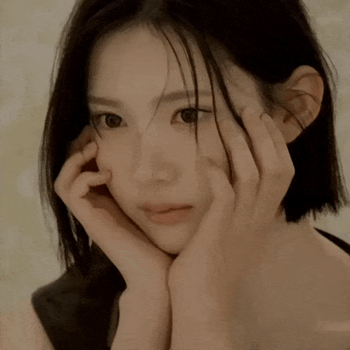 a close up of a woman 's face with her hands on it