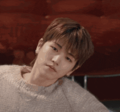 a close up of a young man wearing a sweater and making a funny face .