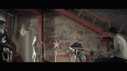 a man playing drums and a woman singing in front of a brick wall
