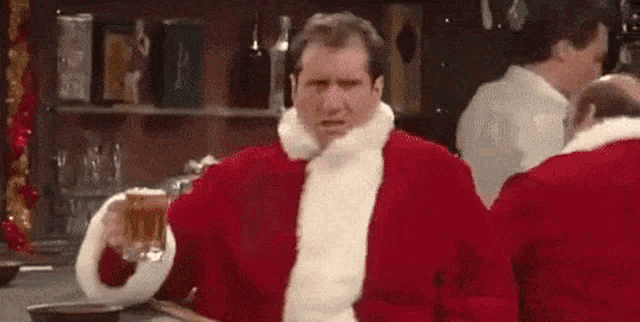 a man in a santa claus costume is holding a mug of beer .