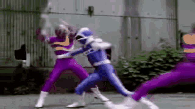 a group of purple and blue power rangers are fighting each other on a street .