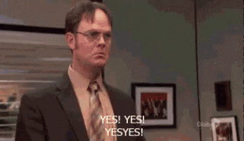 a man in a suit and tie is standing in front of a window in an office and saying yes ! yes ! yes !