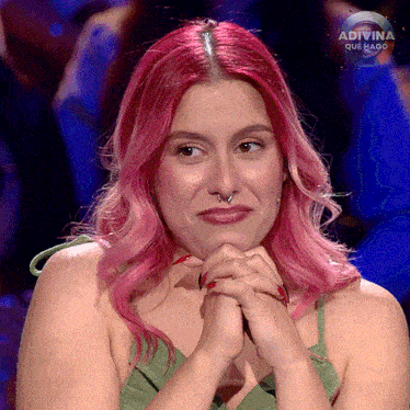 a woman with pink hair is sitting in front of a sign that says " adivina que hago "